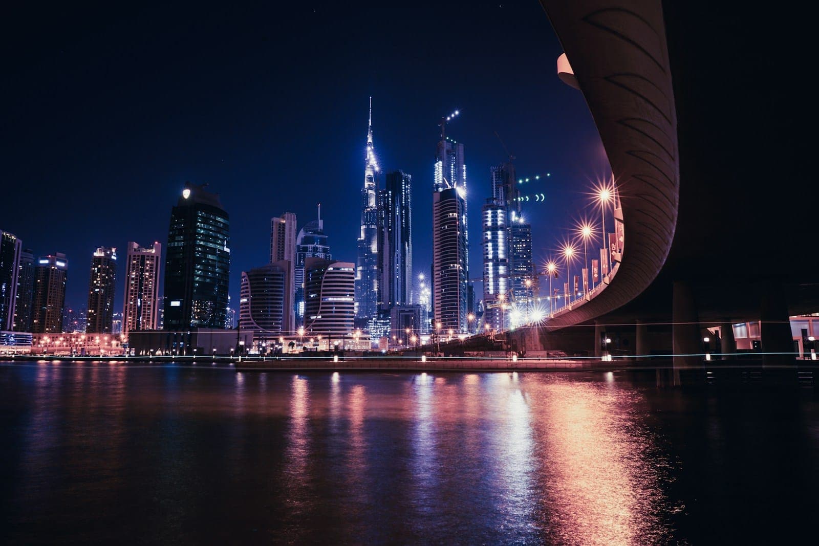 Business Bay at night, with a bridge curving over the water